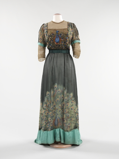 Evening gown by Weeks, 1910. Gown in the collection of, and image via, the Metropolitan Museum of Art. The Paris-based American designer Weeks makes the peacock itself—and not just its feathers—the center of attention on this dress. Embroidered on the bodice and screen-printed on the skirt, the peacock motif is highlighted against the streamlined silhouette of 1910.  The peacock lent itself well to a new era in women’s fashion that embraced Asian influences.   